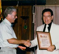 Peter Stallard, the incoming 1990 chair of Raleru (Camera House group) presents outgoing chairman Alan Small, of Taree Camera House,  an appreciation Plaque from members in thanks for all he had done for the Group. (Pic: John Swainston)